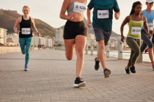 Diverse group of runners competing in a race. Athletes sprinting on a street along the sea.